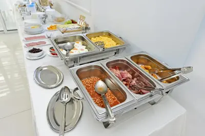 a buffet with several trays of food on a table at Mon Repos Hotel in Ayia Napa