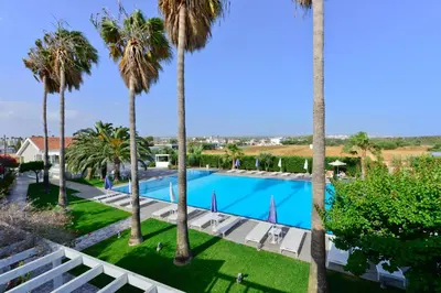 a view of the pool from the balcony of a resort with palm trees at Mon Repos Hotel in Ayia Napa
