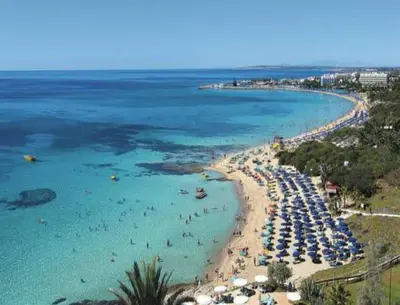 a beach with umbrellas and people in the water at Mon Repos Hotel in Ayia Napa