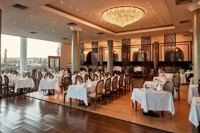 a restaurant with white tables and chairs and a chandelier at Grecian Park in Protaras