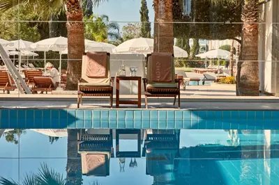 a swimming pool with lounge chairs and a table next to a resort at Grecian Park in Protaras
