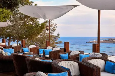 a row of wicker chairs with blue pillows and an umbrella at Grecian Park in Protaras