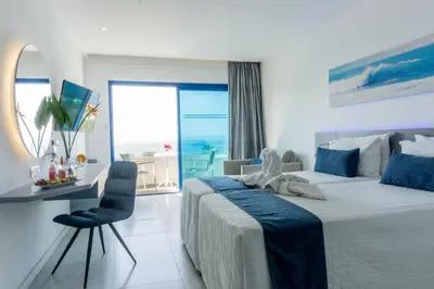 a bedroom with a bed and a desk with a view of the ocean at Anonymous Beach Hotel (Adults 16+) in Ayia Napa