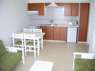 a kitchen with a white table and chairs and a table and a kitchen at Astreas Beach Hotel Apartments in Protaras