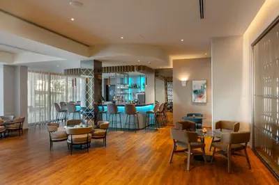 a lobby with tables and chairs and a bar at Faros Hotel Ayia Napa in Ayia Napa