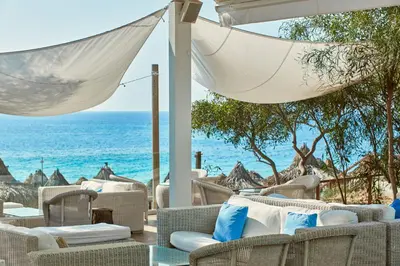 a patio with chairs and the ocean in the background at Grecian Bay in Ayia Napa