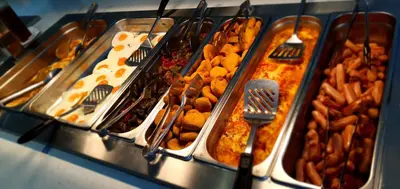 a buffet filled with different types of food in trays at Corfu Hotel in Ayia Napa