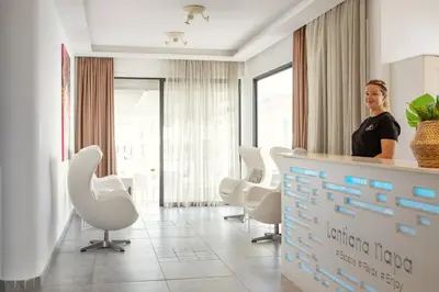 a woman standing behind a counter in a waiting room at Lantiana Napa Aparthotel in Ayia Napa