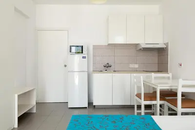 a kitchen with white cabinets and a white refrigerator at Lantiana Napa Aparthotel in Ayia Napa