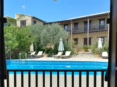 a pool with chairs and umbrellas next to a building at Eveleos Country House in Tochni