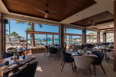 a restaurant with tables and chairs and a view of the beach at Adams Beach Hotel & Spa in Ayia Napa