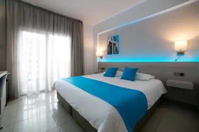 a large bed in a hotel room with blue lighting at Les Palmiers Beach Boutique Hotel & Luxury Apartments in Larnaka