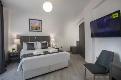 a bedroom with a bed and a tv and a chair at Blazer Residence in Larnaka