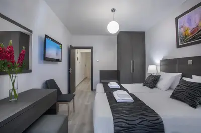 a hotel room with two beds and a living room at Blazer Residence in Larnaka
