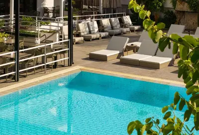 a pool with chaise lounge chairs and a swimming pool at Pefkos City Hotel in Limassol