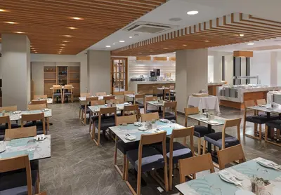 a restaurant with tables and chairs and a kitchen at Pefkos City Hotel in Limassol