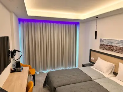 a bedroom with a bed and a table and a window at Papouis Protaras Hotel in Protaras