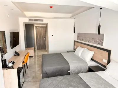 a hotel room with two beds and a television at Papouis Protaras Hotel in Protaras
