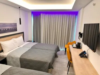 a hotel room with two beds and a desk and a television at Papouis Protaras Hotel in Protaras
