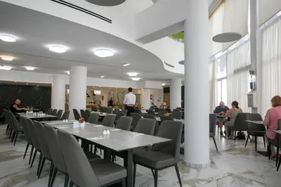 a restaurant with tables and chairs and people sitting at tables at Papouis Protaras Hotel in Protaras