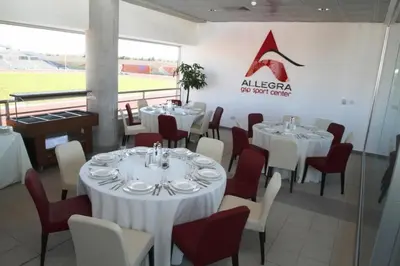 a restaurant with white tables and chairs and a sign at Allegra GSP Sport Center in Nicosia