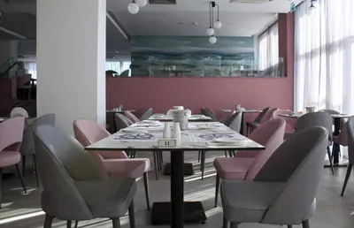 a dining room with a table and pink chairs at Kapetanios Bay Hotel Protaras in Protaras