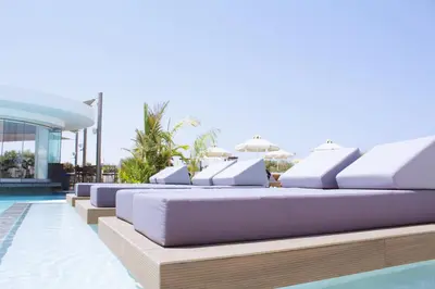 a row of lounge chairs sitting on the side of a pool at Kapetanios Bay Hotel Protaras in Protaras