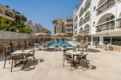 a patio with tables and chairs next to a pool at Cactus in Larnaka