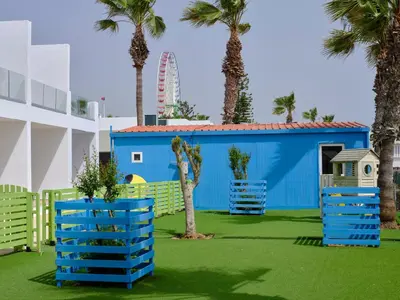 a playground with palm trees and a blue building at Atlantica Panthea Resort in Ayia Napa