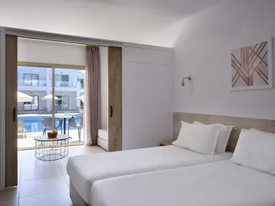 two beds in a hotel room with a balcony at Atlantica Panthea Resort in Ayia Napa