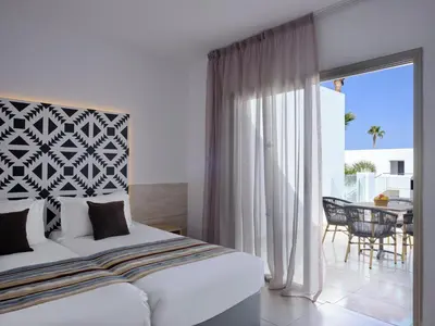 a bedroom with a bed and a balcony with a table at Atlantica Panthea Resort in Ayia Napa