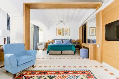 a bedroom with a bed and a blue chair at Columbia Beach Resort in Pissouri