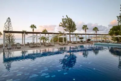 a swimming pool with chairs and the ocean in the background at Columbia Beach Resort in Pissouri