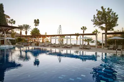 a swimming pool with chairs and umbrellas at a resort at Columbia Beach Resort in Pissouri