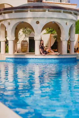 two women sitting on the edge of a swimming pool at Napa Plaza Hotel (Adults Only) in Ayia Napa