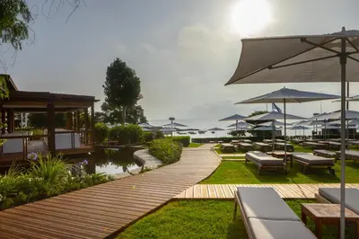 a wooden walkway with benches and tables and umbrellas at Capo Bay Hotel in Protaras