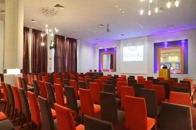 a conference room with red chairs and a screen at Golden Bay Beach Hotel in Larnaka