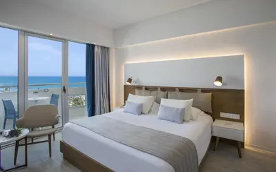 a hotel room with a large bed and a balcony at Lordos Beach Hotel & Spa in Larnaka