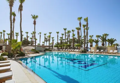 a swimming pool at a resort with palm trees at The GrandResort - Leonardo Limited Edition in Limassol