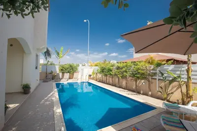 a swimming pool with an umbrella next to a building at George's Lux Villa in Protaras