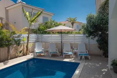 a group of chairs and an umbrella next to a pool at George's Lux Villa in Protaras