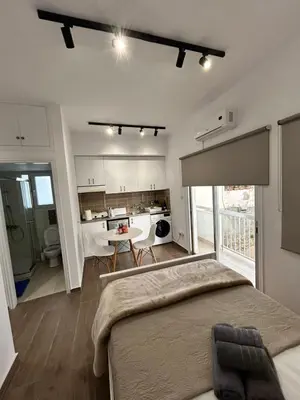 a bedroom with a bed and a kitchen with a table at Harmony Studios in Larnaka