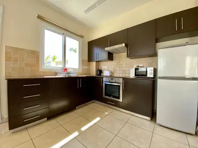 a kitchen with brown cabinets and a white refrigerator at Sunny Cyprus in Paralimni