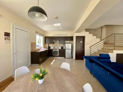 a kitchen and living room with a table and a blue couch at Sunny Cyprus in Paralimni