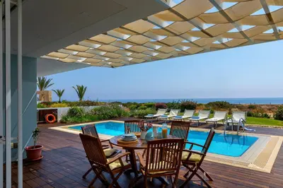 a patio with a table and chairs and a pool at Protaras Beachfront Villa Alia in Protaras
