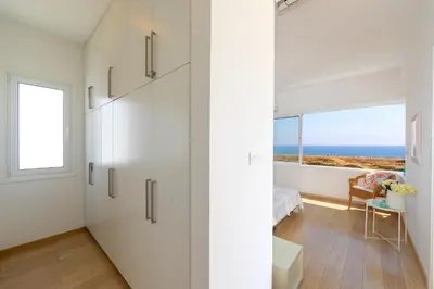 a bedroom with white cabinets and a view of the ocean at Protaras Beachfront Villa Alia in Protaras