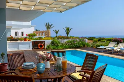 a patio with a table and chairs next to a swimming pool at Protaras Beachfront Villa Alia in Protaras