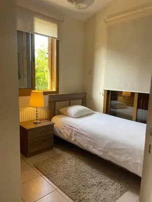 a bedroom with a bed with a lamp and a window at Alkinoou Residence in Limassol