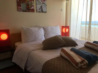 a bed with pillows and two lamps in a bedroom at Alex Beach Apartment 51 in Larnaka