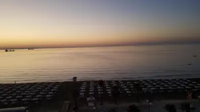 a sunset over the water with a lot of umbrellas at Alex Beach Apartment 51 in Larnaka